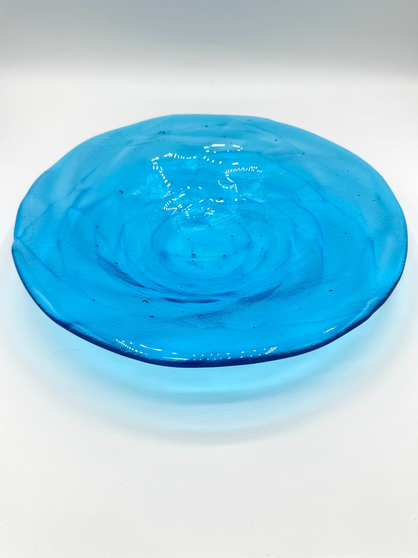 Blue glass plate with swirling pattern on a white background