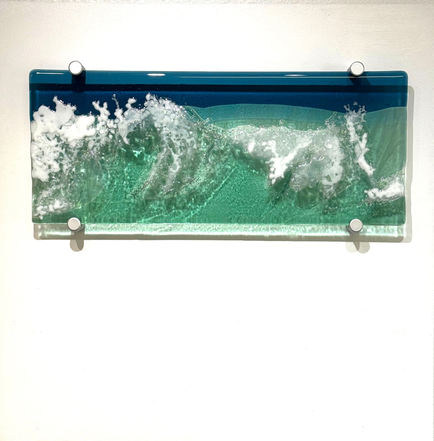 Glass art panel depicting the Ocean full of crashing waves, Multiple textures allow light to shine through and create shimmering details.