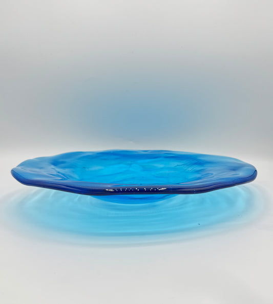 Blue glass wide brim shallow bowl on a white background
