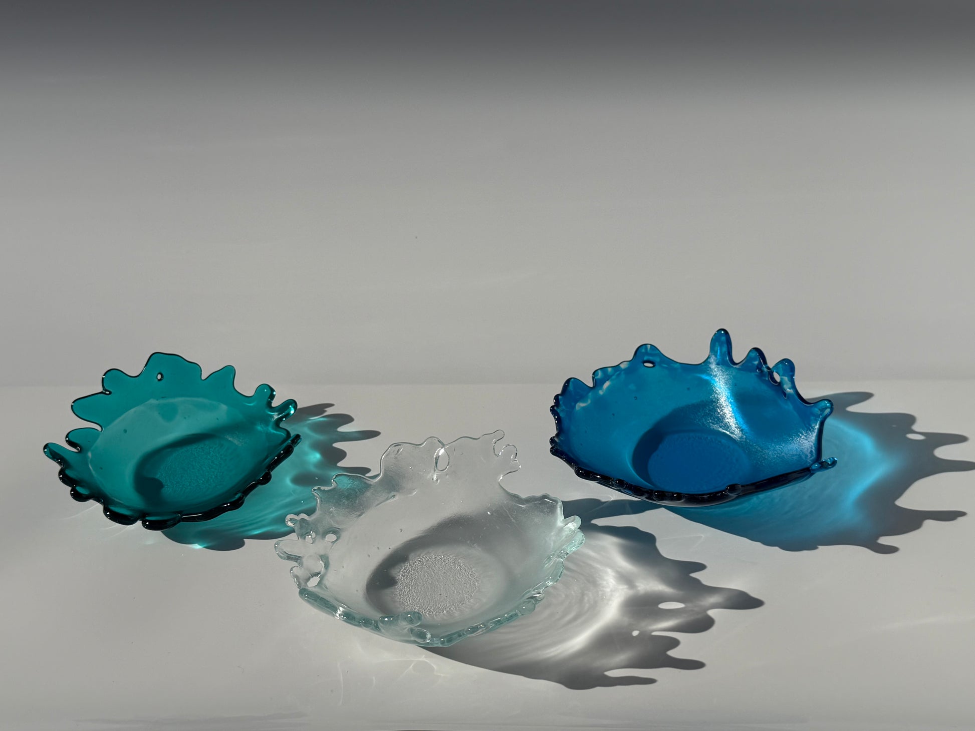 Three blue glass art pieces on a white background