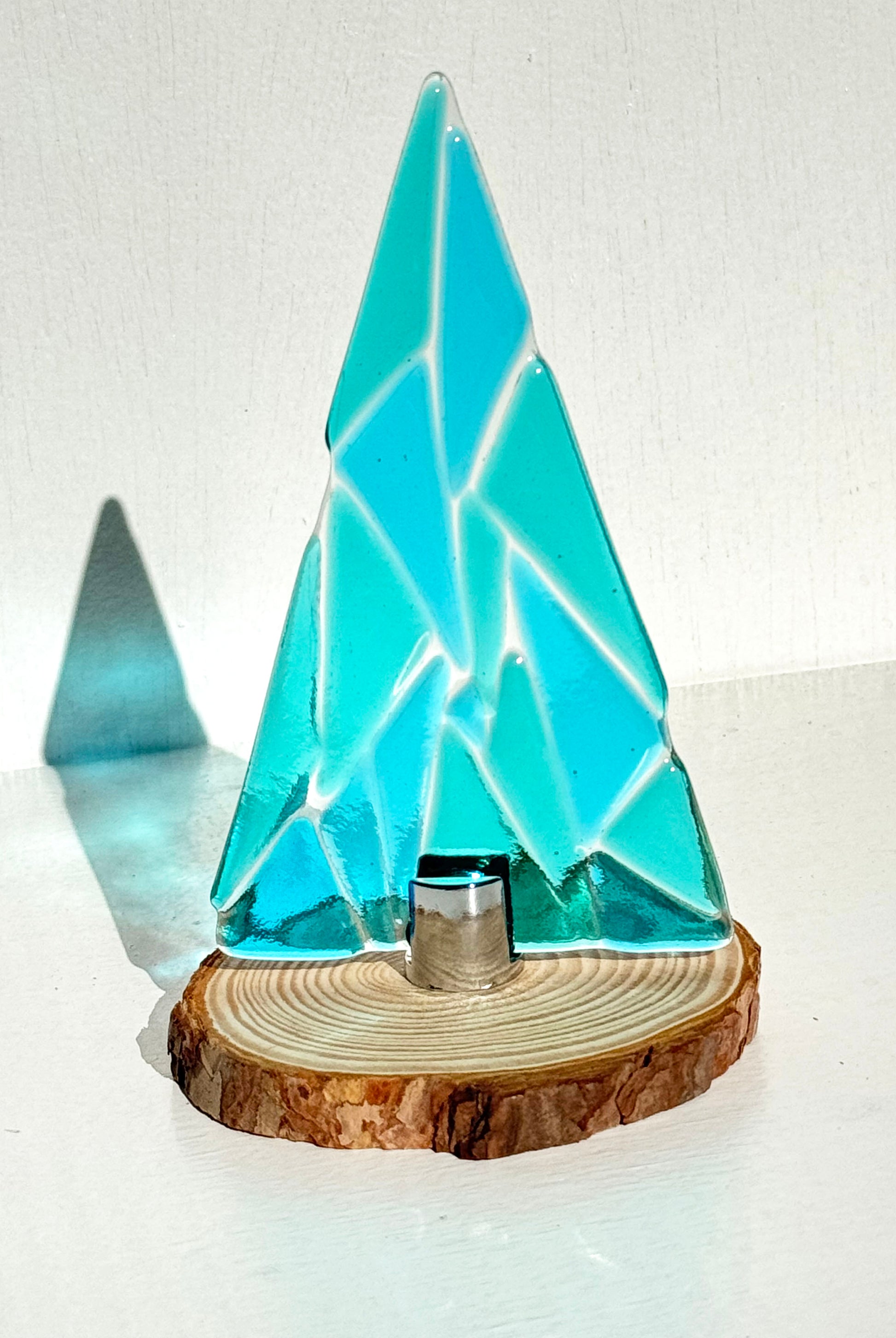 Small Carribean sky table top tree is made up of sky blue and Carribean green glass. Each of the triangular shapes holds a smooth texture that can be felt popping up ever so slightly from the clear glass. 
