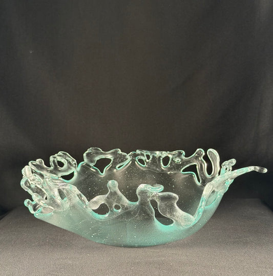Decorative glass bowl with cut-out designs resembling splashing water on a dark background