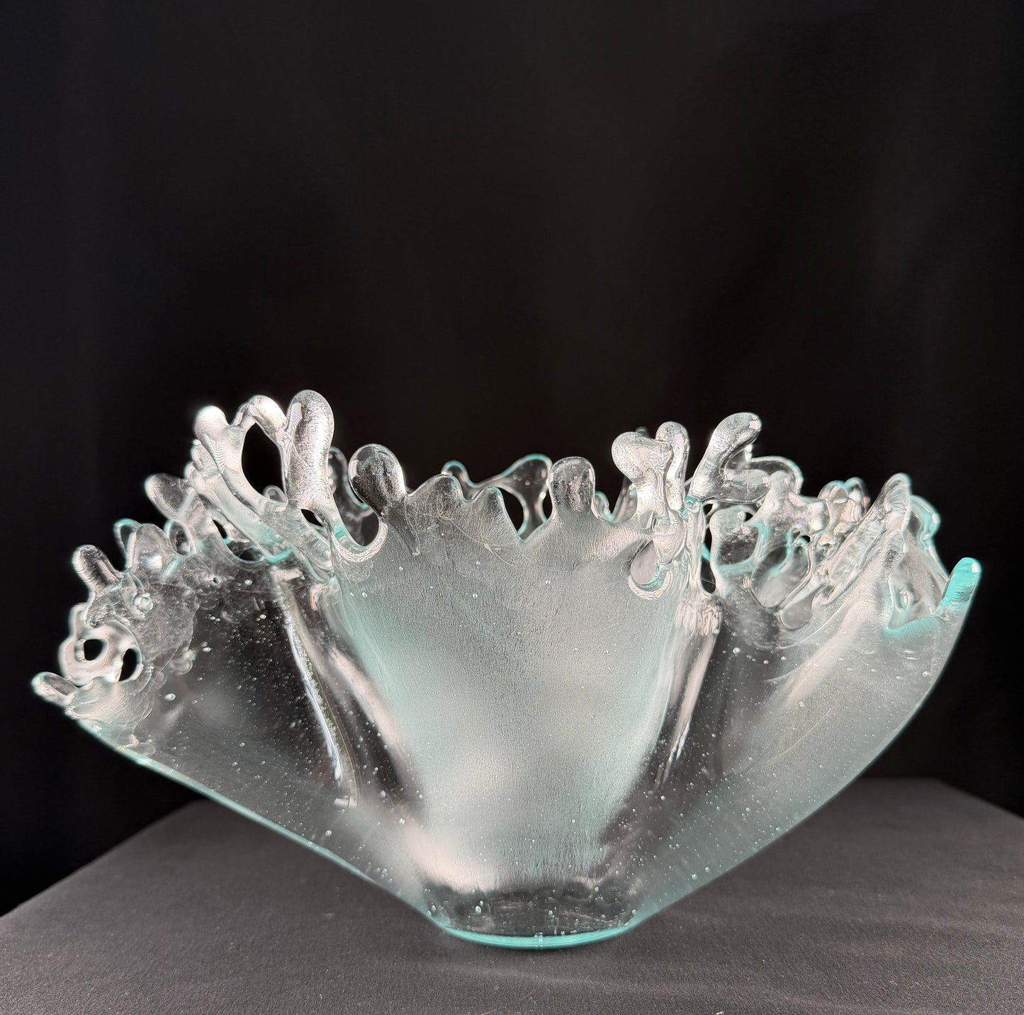 Clear glass sculpture with intricate designs on a black background