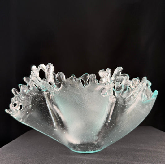 Clear glass sculpture with intricate designs on a black background