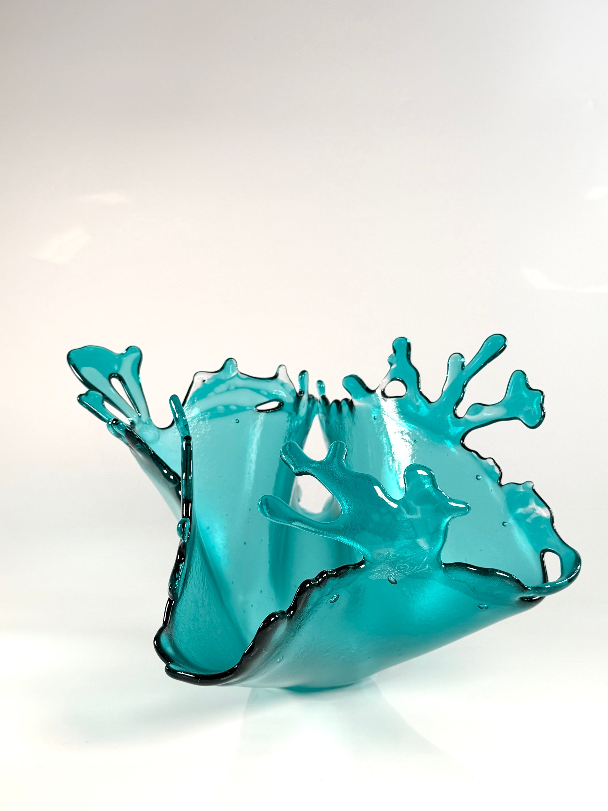Turquoise glass sculpture on a white background