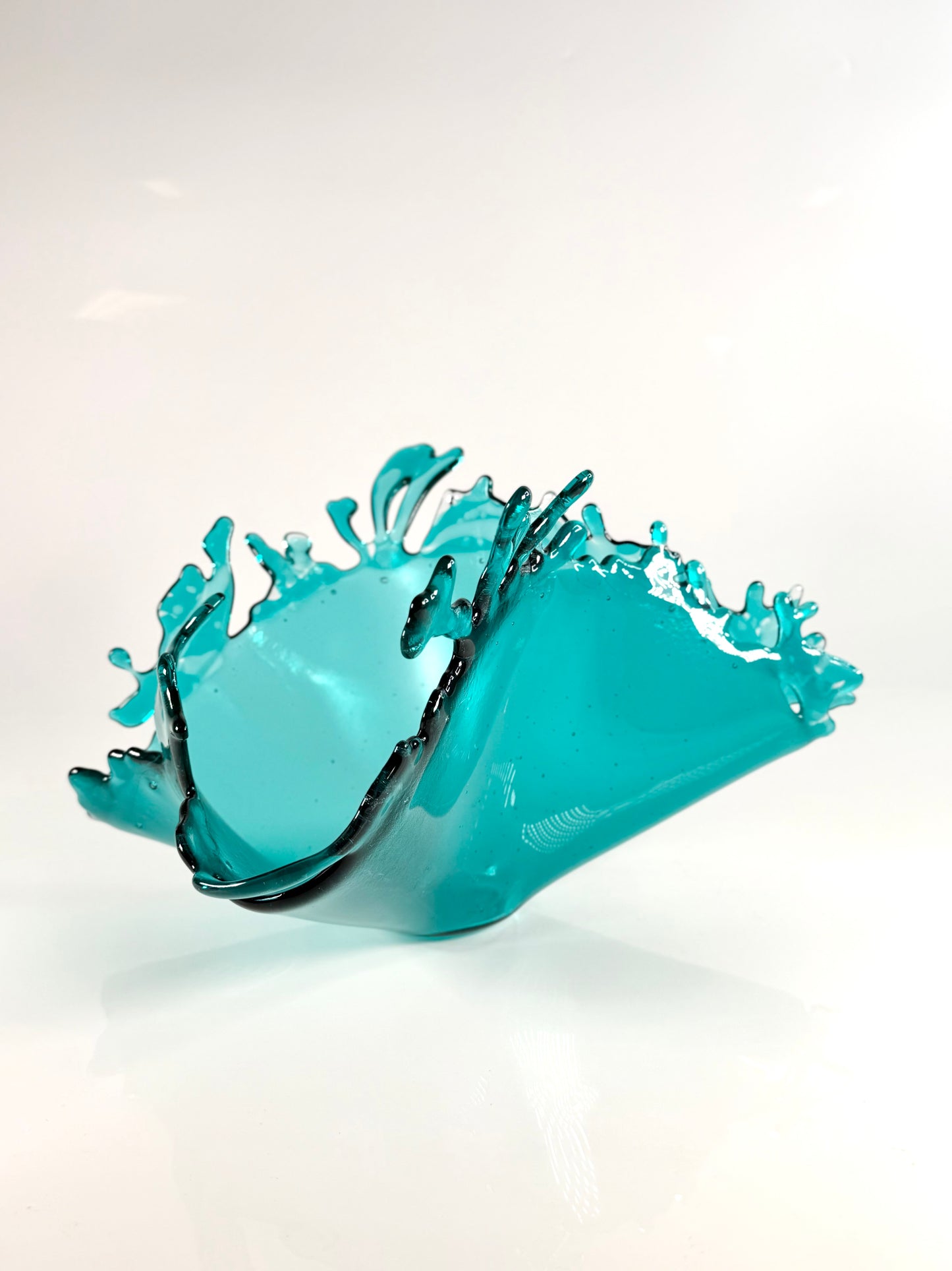 Turquoise glass bowl with wave design on a white background