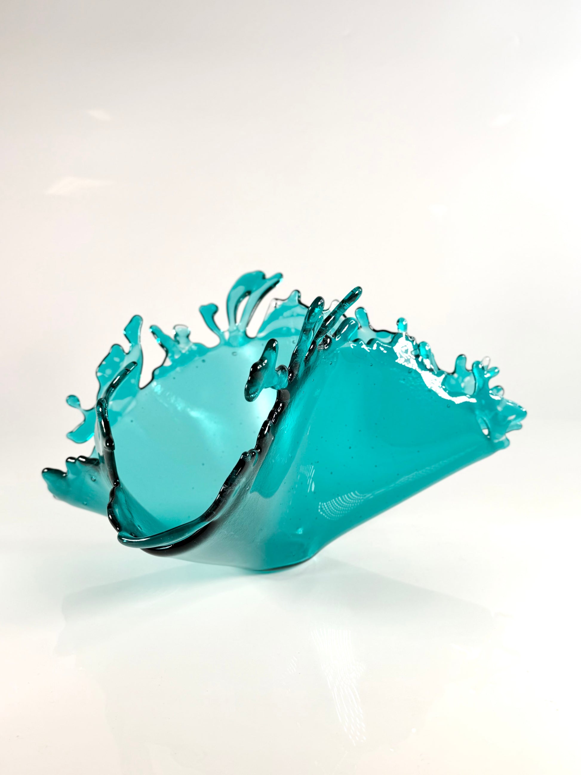 Turquoise glass bowl with wave design on a white background