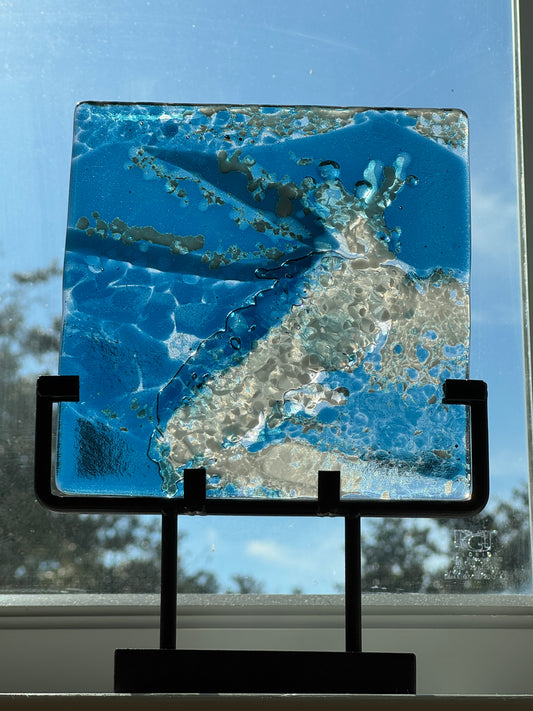 Glass panel showing a crashing wave in the middle of the ocean. Shown in window with sunlight to backlight 