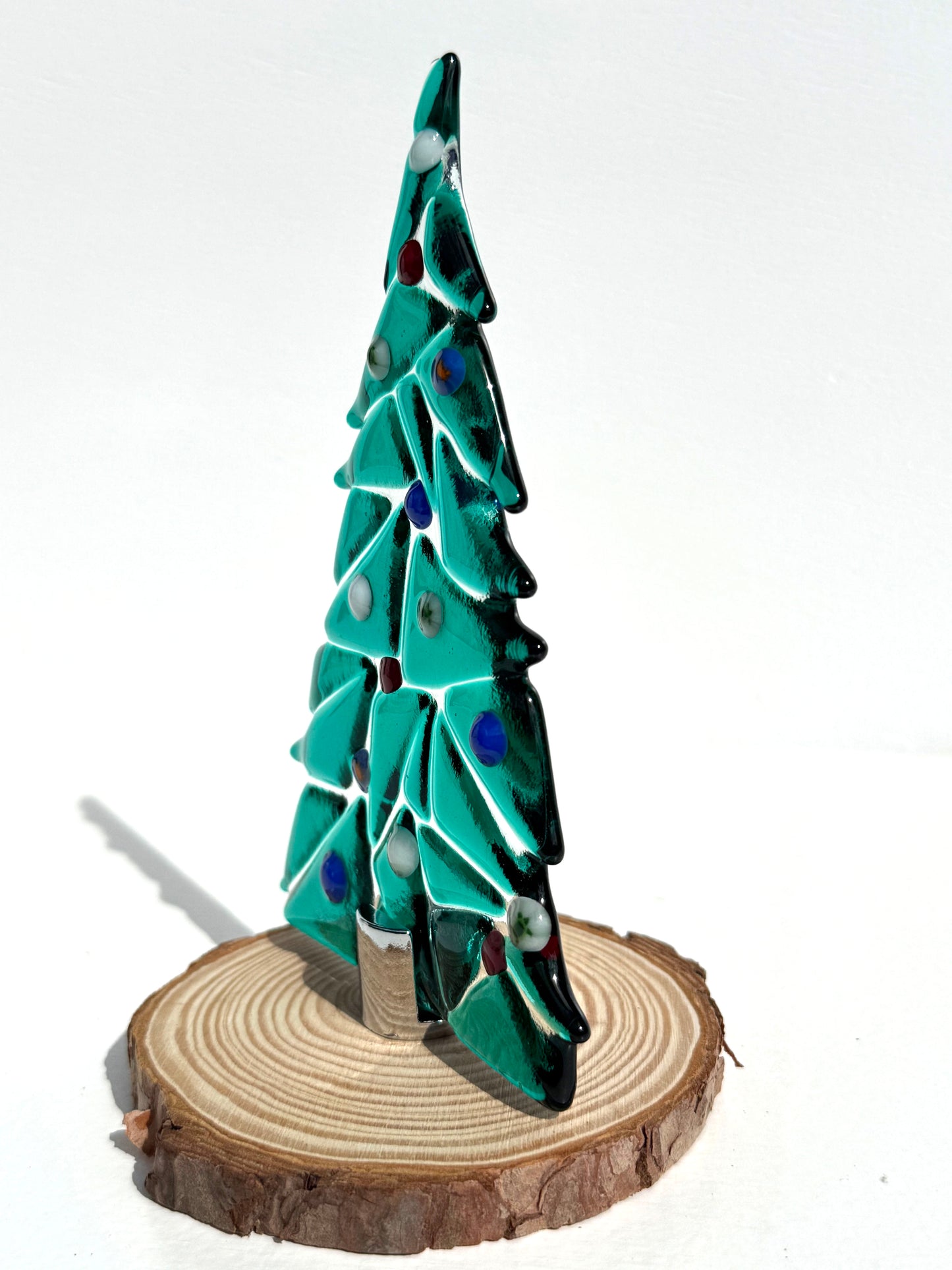 Side view of a sea green table top glass tree with turtle, crab, white, blue, and red ornaments.
