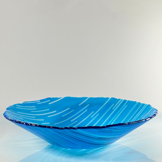 Blue glass bowl with wavy design on a light gray background