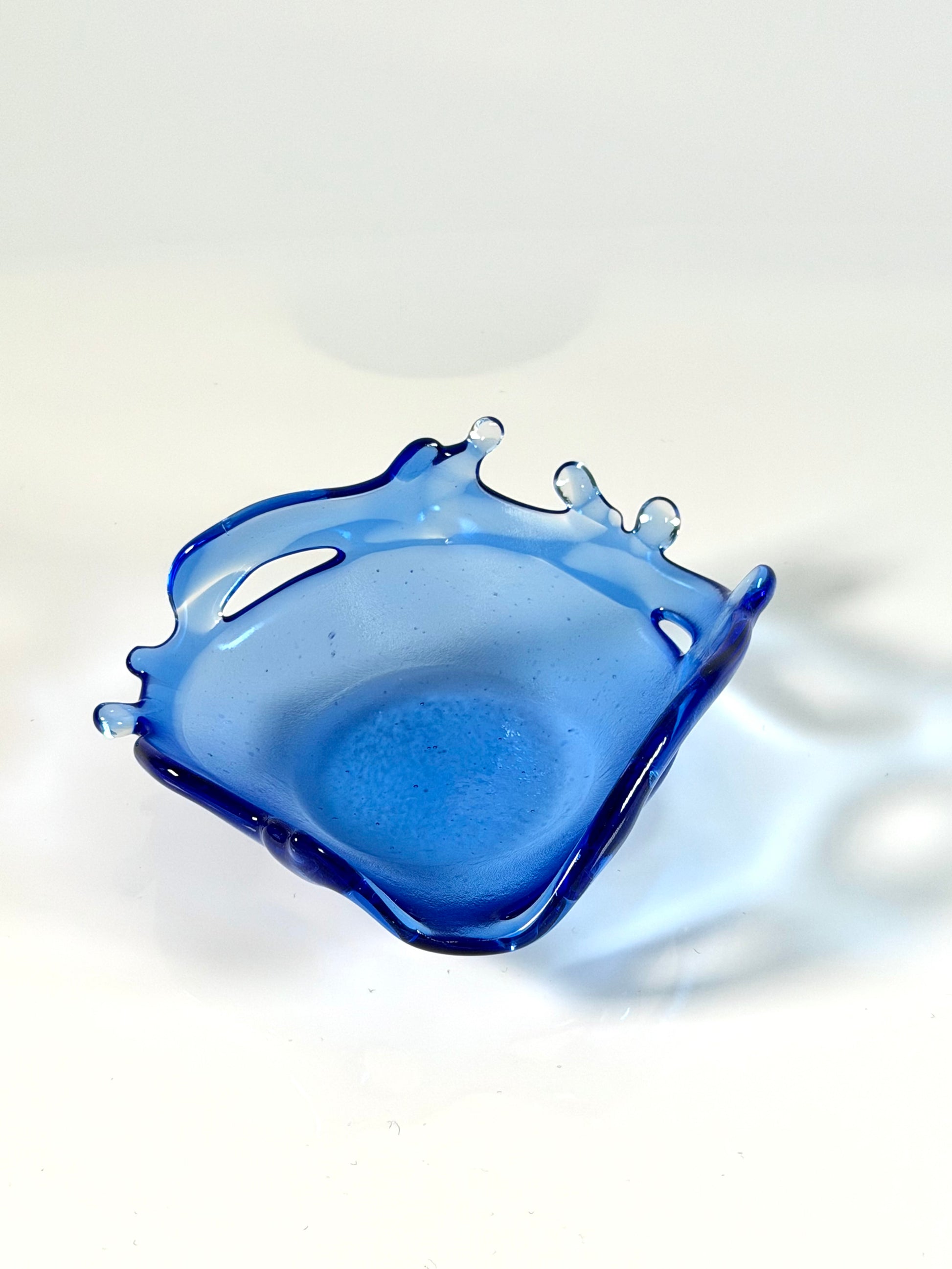 Blue glass dish with a unique design on a white background
