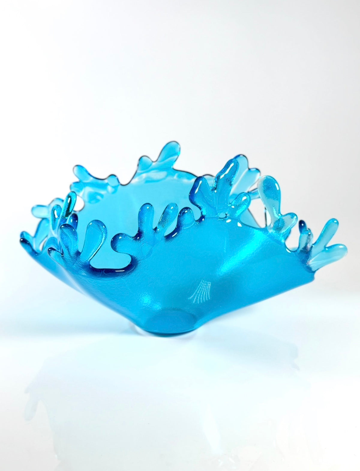 Side view of sculpture depicting splash of water. This view shows one of the shorter sides along with one of the longer sides on a white backdrop. 