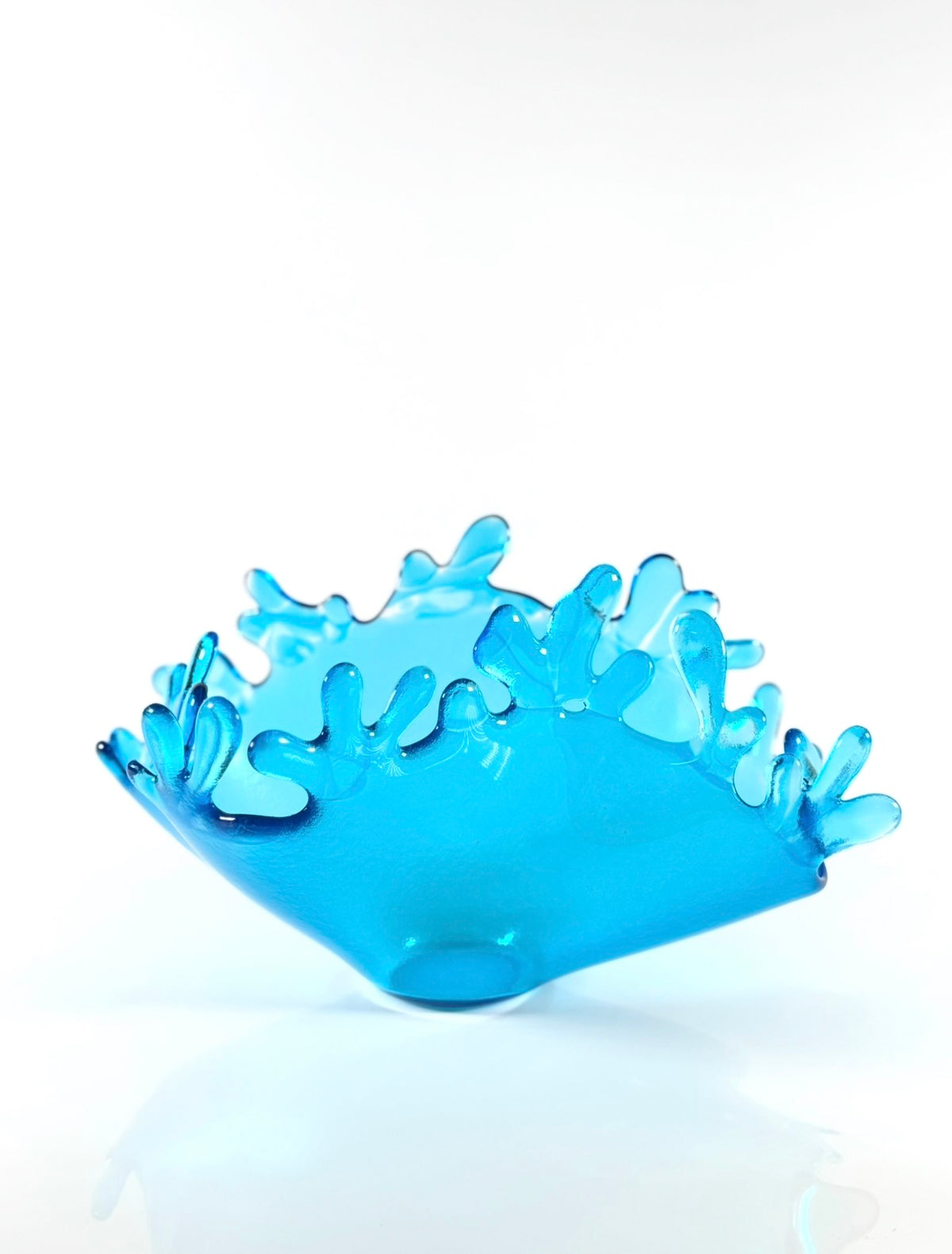 Glass sculpture depicting water being splashed upward. Shown on white background.