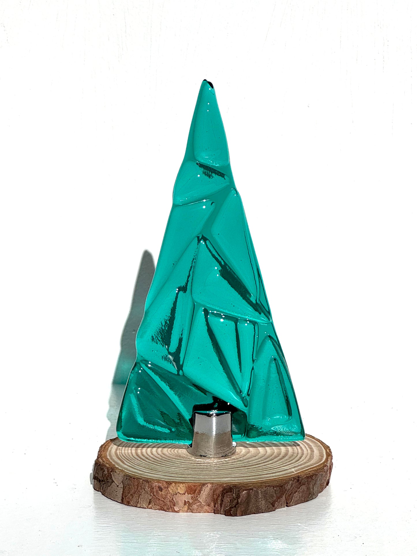 Teal glass tree mounted on a small wood unfinished round to allow to stand on a table top. Texture can be seen and felt by smooth layers of glass.