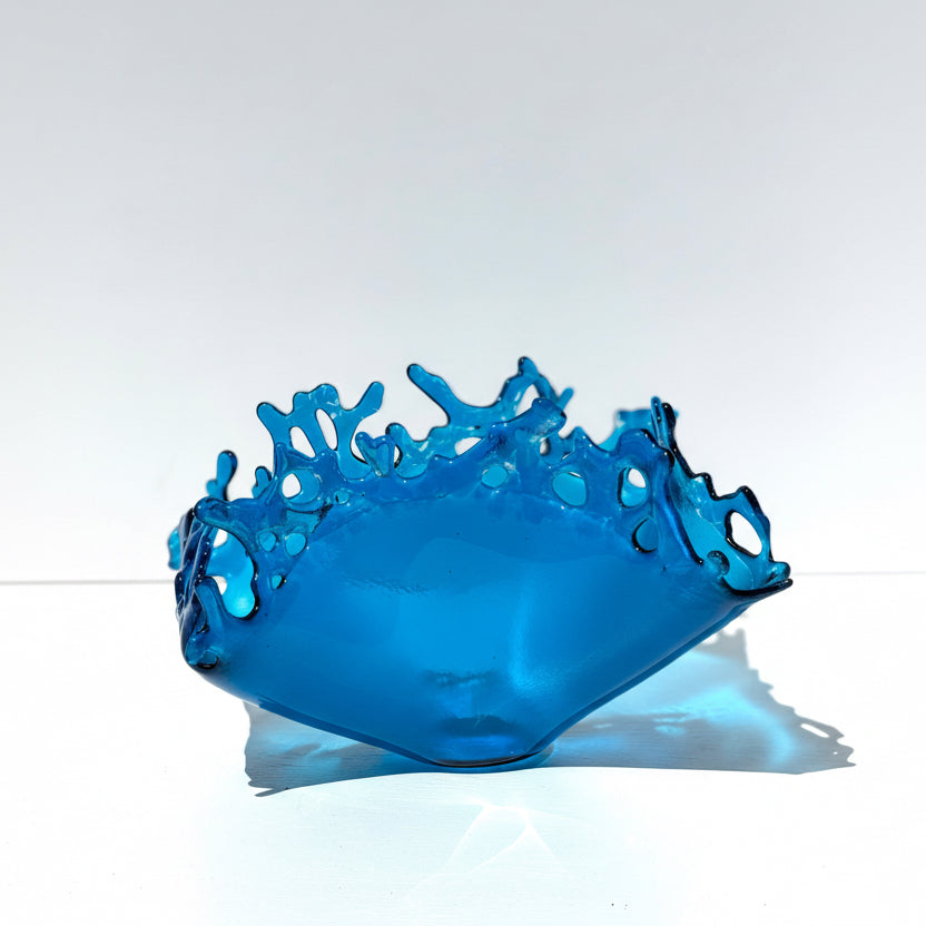 Blue Glass sculpture with a unique design of water splashing upward on white background