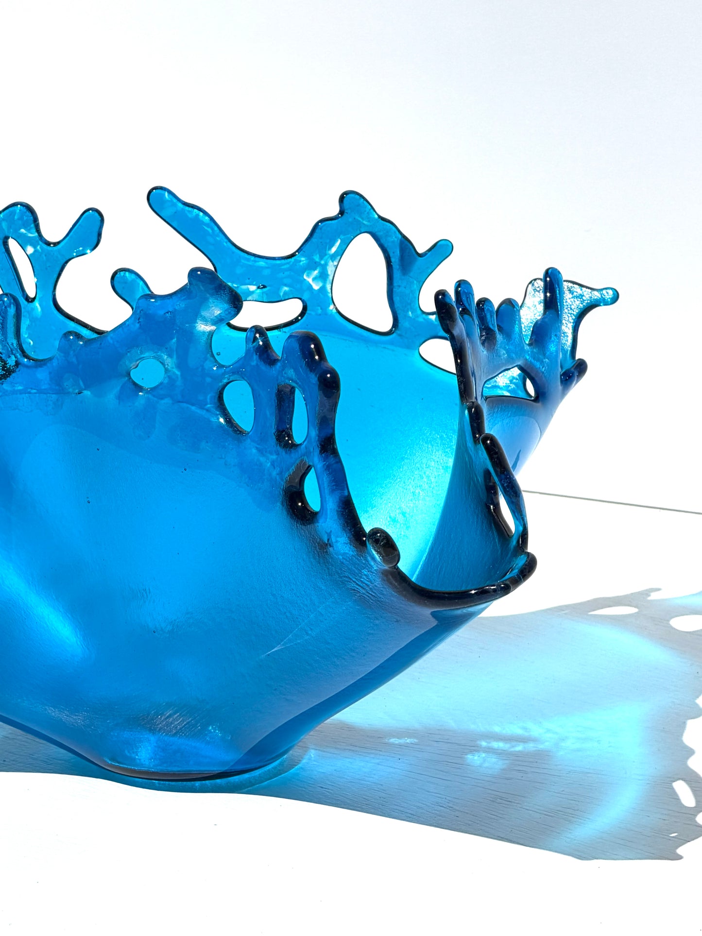 Close up of a transparent blue sculpture that looks like water on white background 