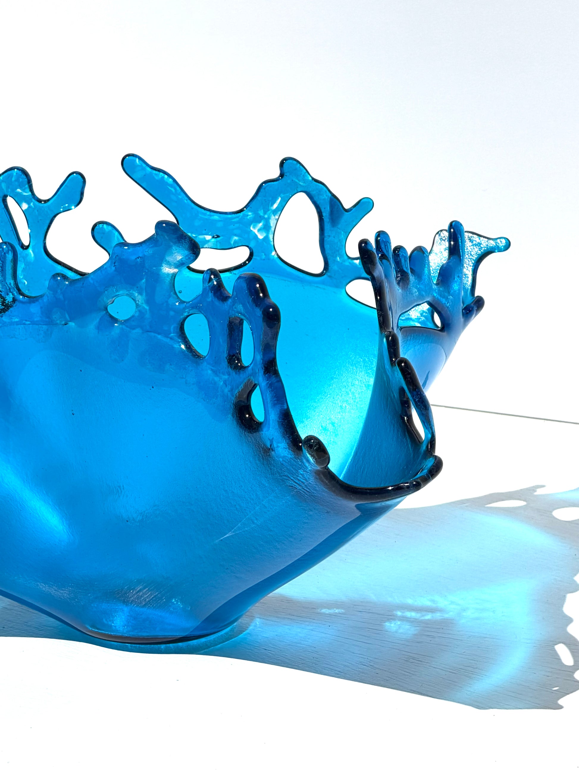 Close up of a transparent blue sculpture that looks like water on white background 