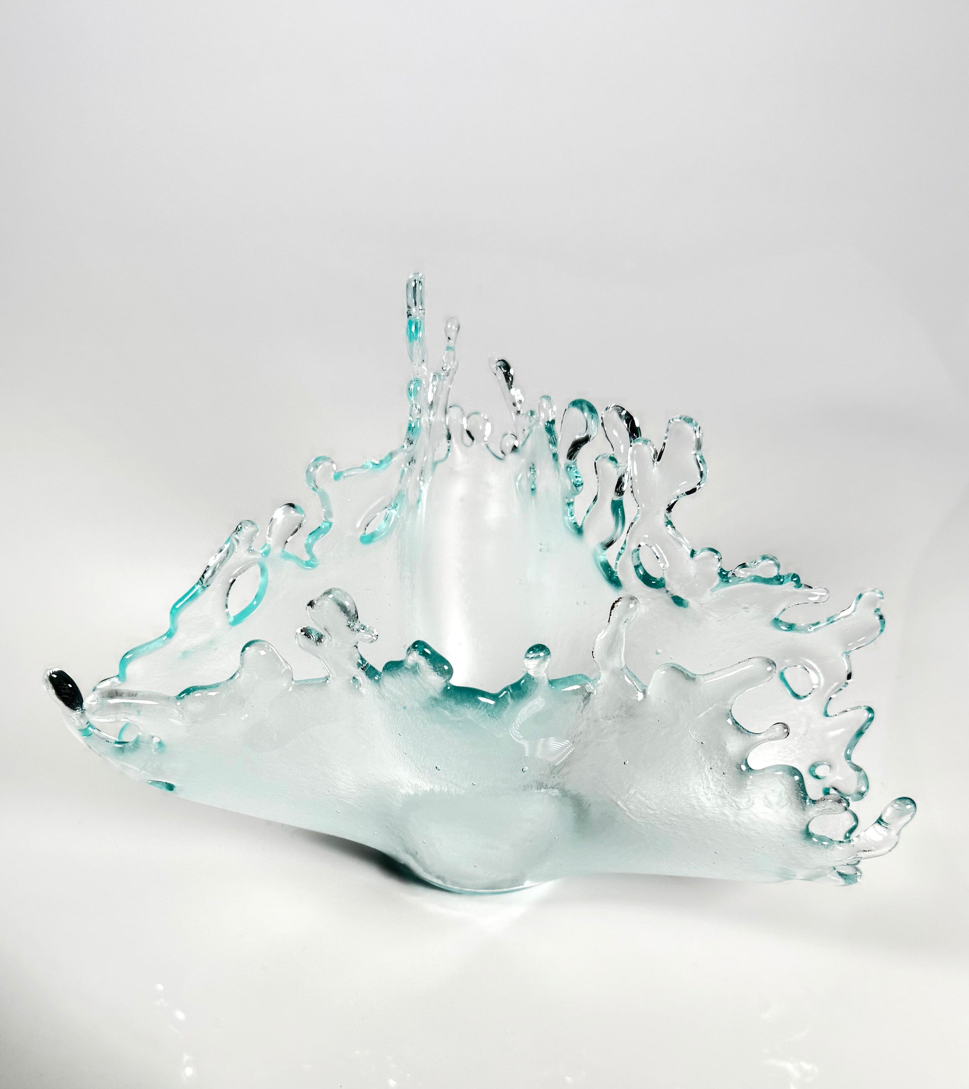 Glass sculpture of a splash on a white background looking down from above
