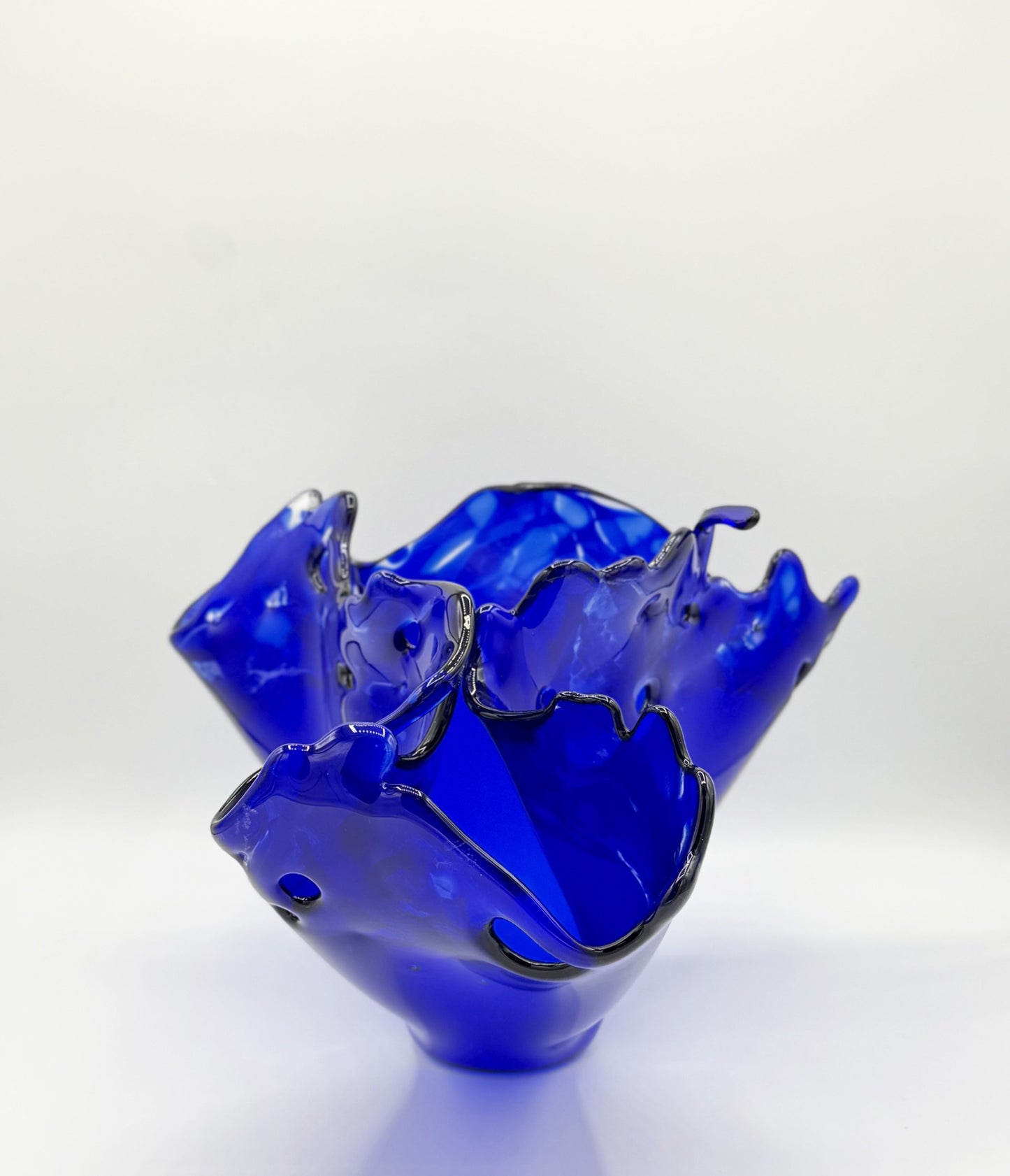 Blue glass bowl with wavy edge on a white background