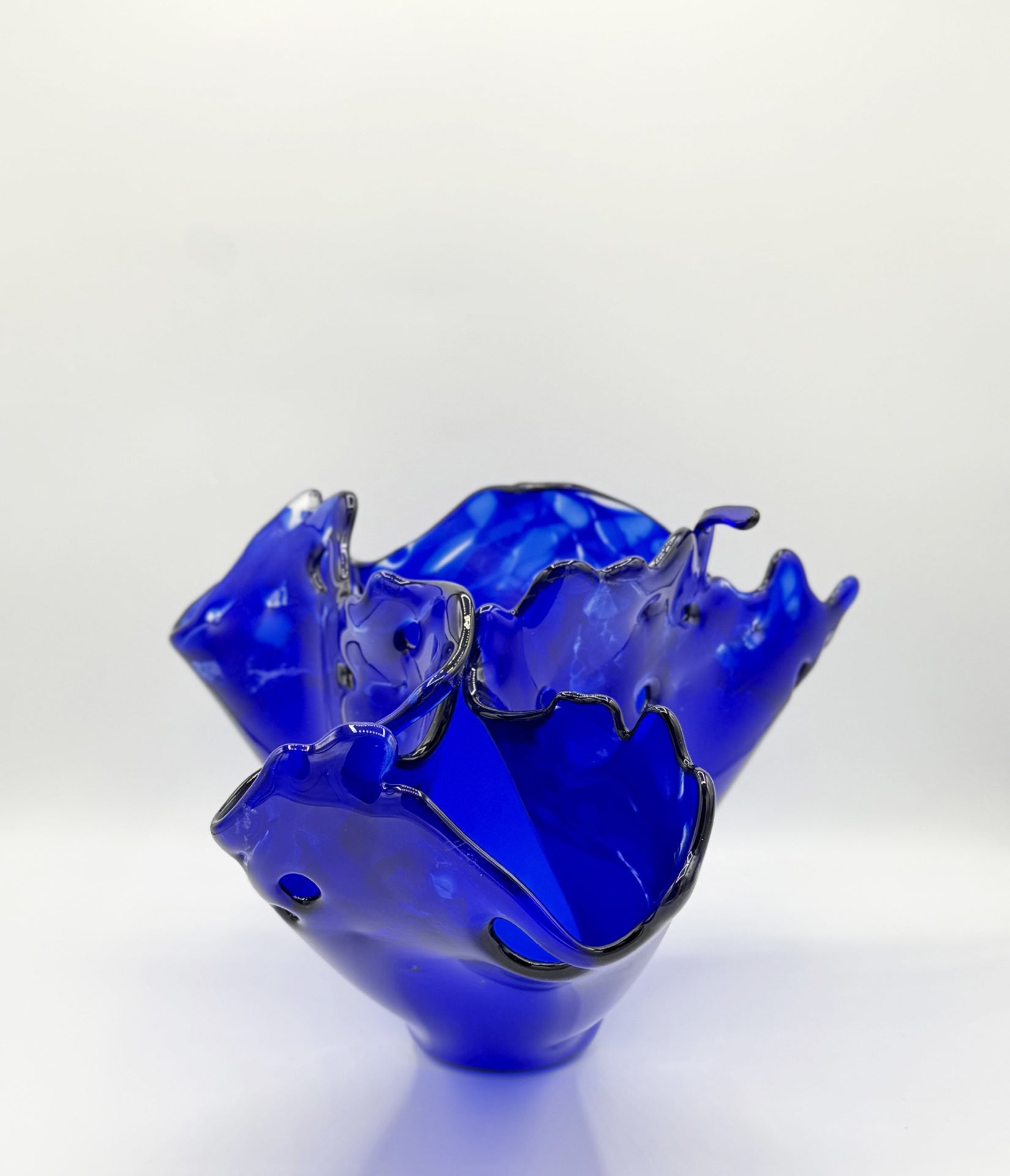 Blue glass bowl with wavy edge on a white background