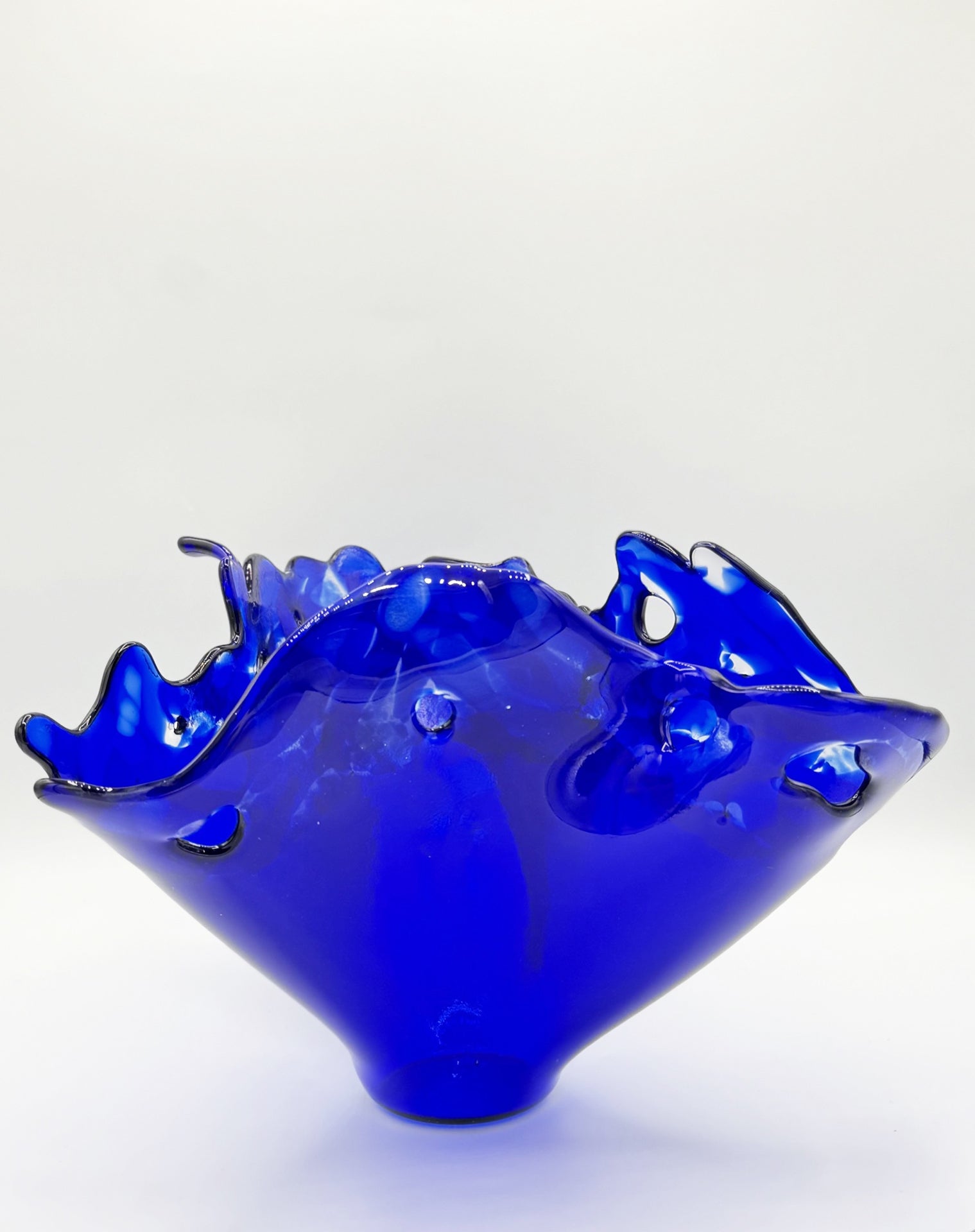 Blue glass bowl with wavy design on a white background depticting water in motion